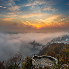 Budapest, Hungary - Mysterious foggy sunrise with Liberty Bridge (Szabadsag hid) and lookout on Gellert Hill and hazy skyline of Budapest at autumn morning