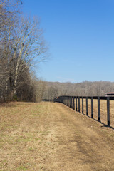 Fototapeta premium Perspective view of black fencing in a winter landscape, vertical aspect