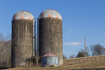 Two old concrete grain silos on a hillside, blue sky winter, horizontal aspect © Natalie Schorr