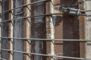 Very close oblique view of metal straps around an old concrete silo, horizontal aspect