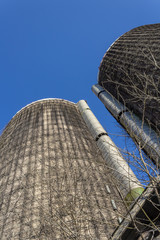 View looking up the face of two old concrete silos against a blue sky, vertical aspect