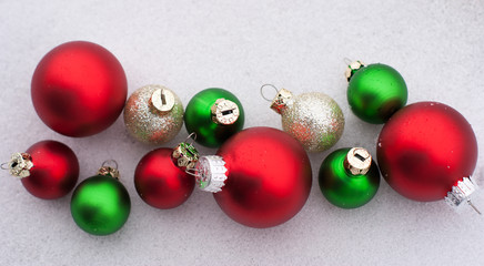 Group of 5 red ornaments with green and gold ornaments with a background of snow