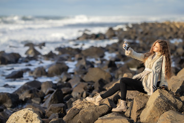 A young girl on the shore of a stormy sea is photographed on a tourist trip around Sakhalin Island walking along the shore admiring nature.