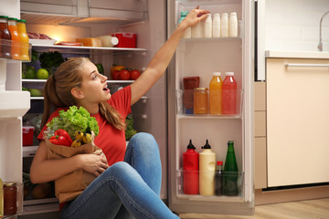 Young woman choosing food in refrigerator at home