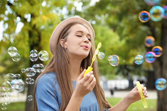 Young woman blowing soap bubbles in park