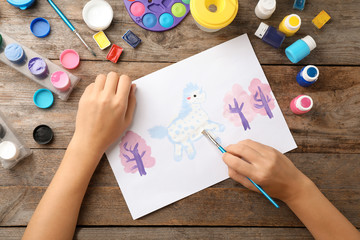 Girl painting picture of unicorn on table, top view © New Africa
