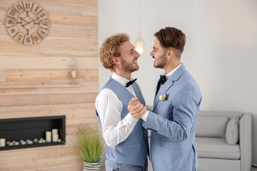 Happy newlywed gay couple dancing at home