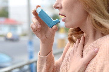 Woman using asthma inhaler outdoors, closeup. Health care - obrazy, fototapety, plakaty