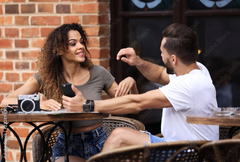 Poster Lovely young couple looking at smart phone at cafe