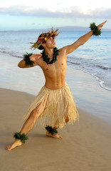 Male Hula Dancer performing on the beach next to the waters edge.