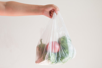 Hand holding a plastic bag of vegetables