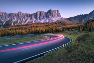 Blurred car headlights on winding road in mountains at sunset in autumn. Spectacular landscape with...