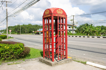 Red telephone booth is empty, old model On the edge of the highway