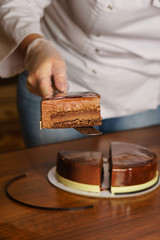 Prague mousse cake. Woman shows the filling and sponge cake. Mirror glaze glitters deliciously. Modern cooking. Cooking in a pastry shop.
