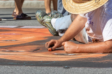 Male artist drawing with chalk on street during autumn festival. - Powered by Adobe