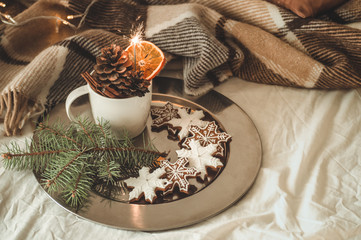 cup with cones and dry orange with sparkler, fir branch, Christmas cookies, cozy knitted blanket, New Year, Christmas still life.