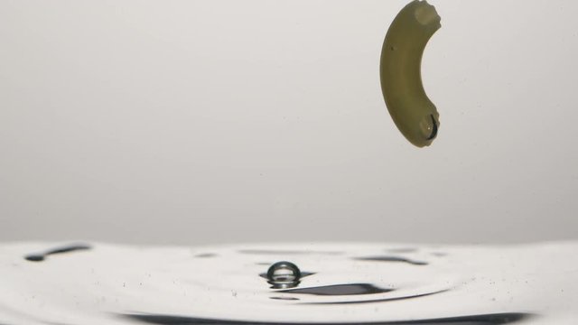 Inverted picture of falling pasta in water on white background - Slow motion