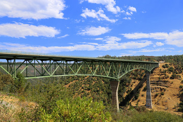 bridge crossing canyon with blue sky and clouds