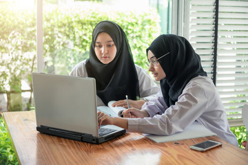 Young muslim students working with computer in the room.
