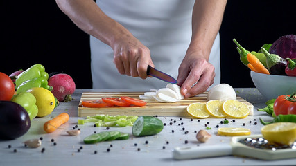 Man is cutting vegetables in the kitchen, slicing black radish