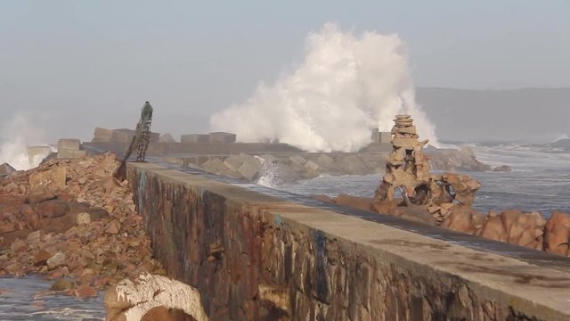 Rompeolas y ola rompiendo en un d&iacute;a de temporal