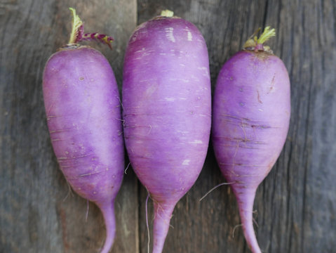 Three Purple Radishes On A Rustic Wood Table 