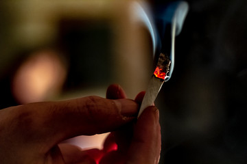 A hand passing a marijuana cigarette or joint while it is burning