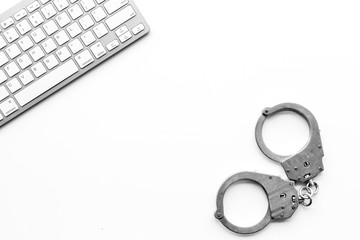 Cyberfraud concept. Handcuff near keyboard on white background top view copy space