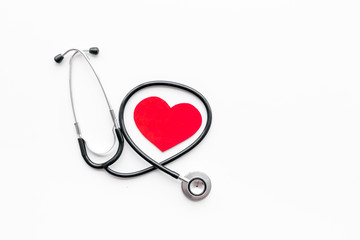 Heart disease concept. Stethoscope near heart sign on white background top view copy space
