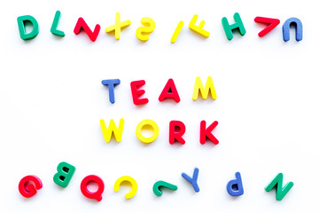 Teamwork training concept. Text teamwork lined with colored letters near toy letters on white background top view space for text
