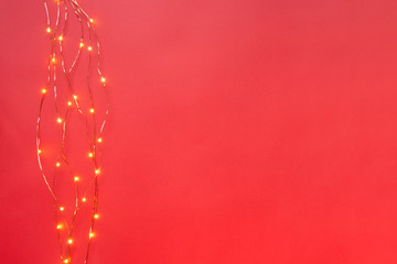 Christmas lights garland border over red background. Flat lay, copy space.