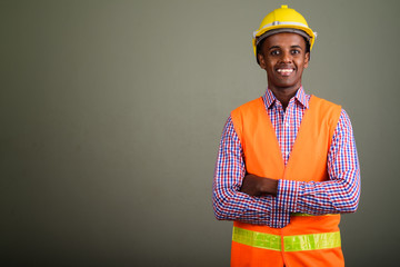 Young handsome African man construction worker against colored b