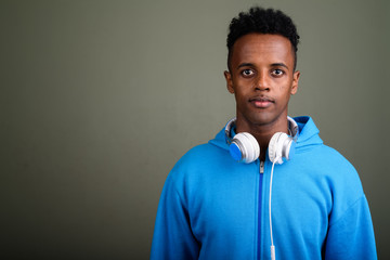 Young handsome African man wearing headphones against colored ba