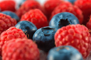 Blueberries and raspberries mix background. Ripe and juicy fresh raspberries and blueberries close-up. A lot of berries close-up.