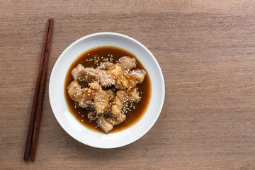 top view of pork belly with teriyaki sauce in a ceramic dish on wooden table. asian homemade style food concept.