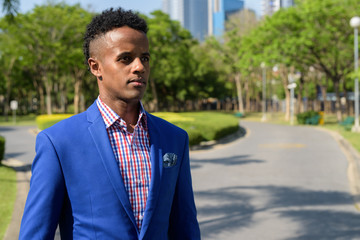 Young handsome African businessman relaxing at the park in Bangk