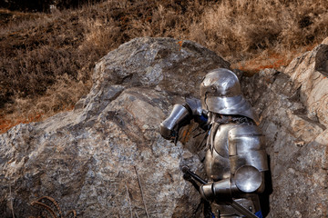 Knight with a sword and in medieval armor on the background of granite stone