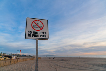 Do not step in fire pits sign on beach in sunset
