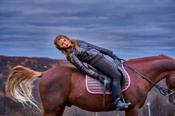 Obraz premium Portrait of a young beautiful woman with long brown hair. Woman on a horse walk in the forest.