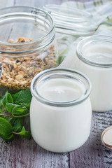 Two glass jarы with greek yogurt and jar with homemade oat granola for healthy breakfast
