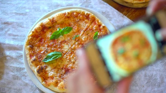 Woman in a restaurant make photo of food, pizza with mobile phone camera. Hands of female making a photo of pizza on a smartphone in cafe. Man Taking Food Photo of pizza into social networks. slow