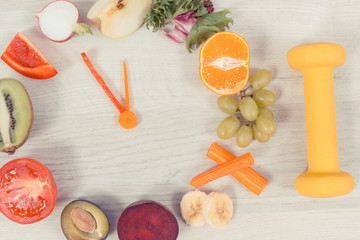 Dumbbell and clock made of fruits and vegetables, time to diet and sporty lifestyle concept