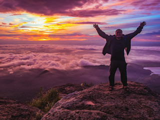 Fototapeta premium Podróżnik stanąć na Rocky cilff z sunsire sky i pięknym morzem chmur na "Pa na rai" Khao Luang Mountian Ramkhamhaeng National Park, Sukhothai Province Thailand