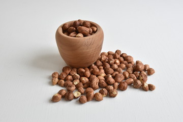 Closeup of hazelnuts in the wooden bowl on the white table