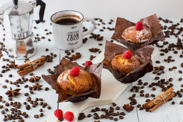 three muffins, a cup of coffee, cinnamon, coffee pot, coffee beans, a label for text on a white table