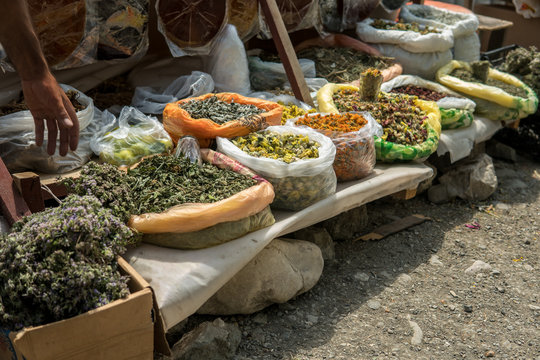 Bunches of healing dried herbs, sour lavash and mortar for sale.