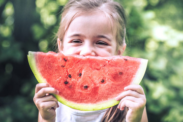 a little girl holding a piece of watermelon