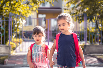 Children go to school, happy students with school backpacks and holding hands together