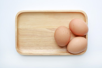 Chicken three eggs on wooden tray isolated on white background.