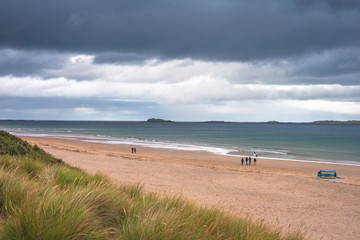People walking on blue flag Whiterocks beach, Portrush, Northern Ireland